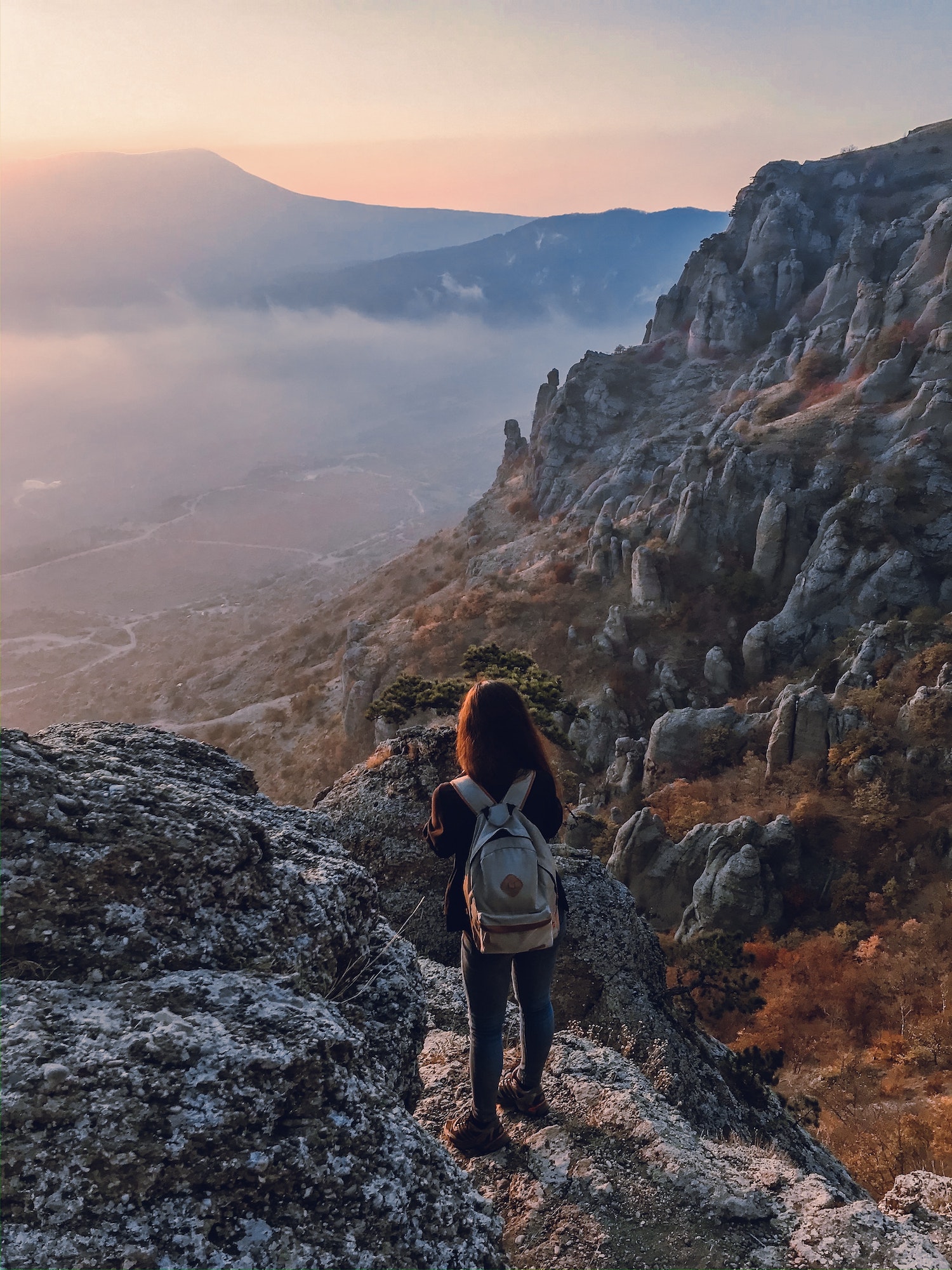 Inspirational mountain view of a sunset, discovered by a girl with a backpack
