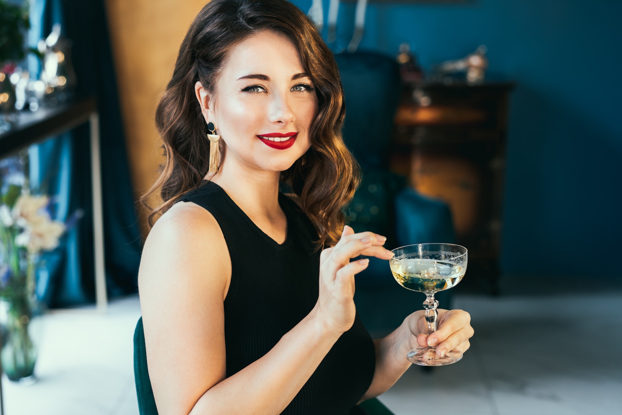 Portrait of posh elegant woman in evening dress with a glass of champagne in the luxury interior